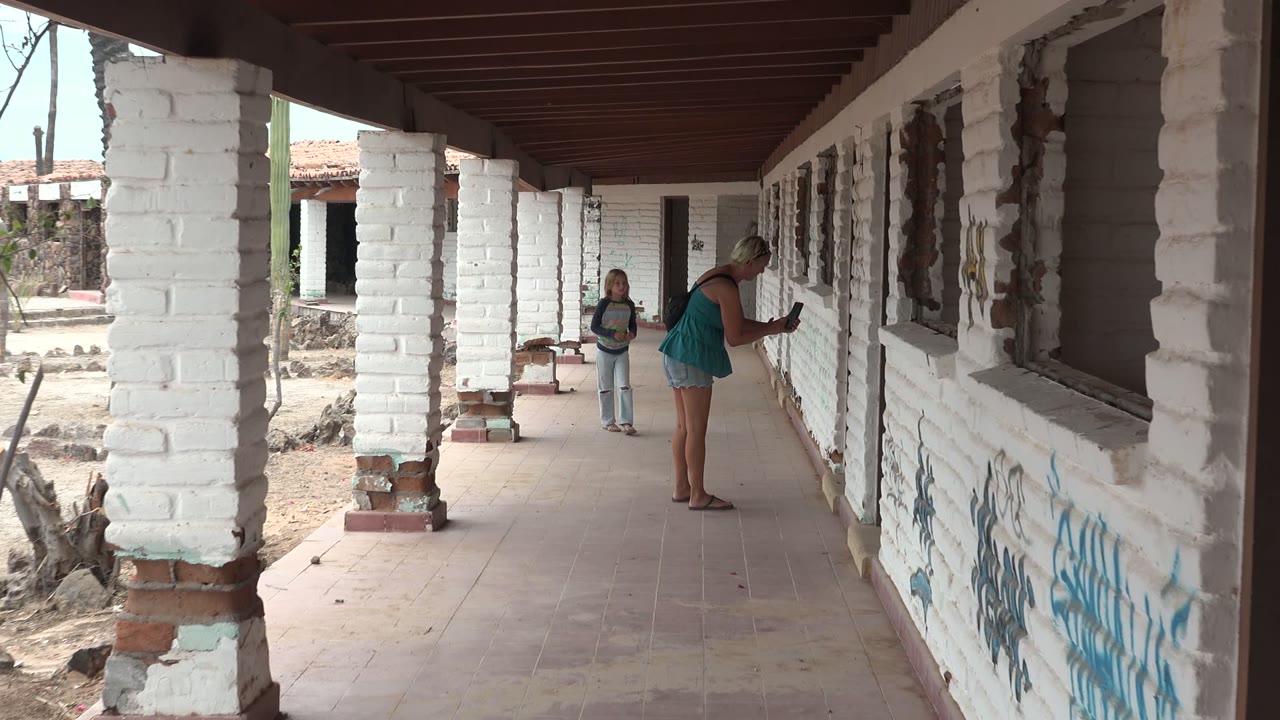 Child stands in the corridor while woman checks the wall or window area.