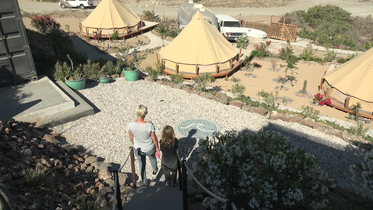 Couple begins moving down steps toward the gravel area and tents.