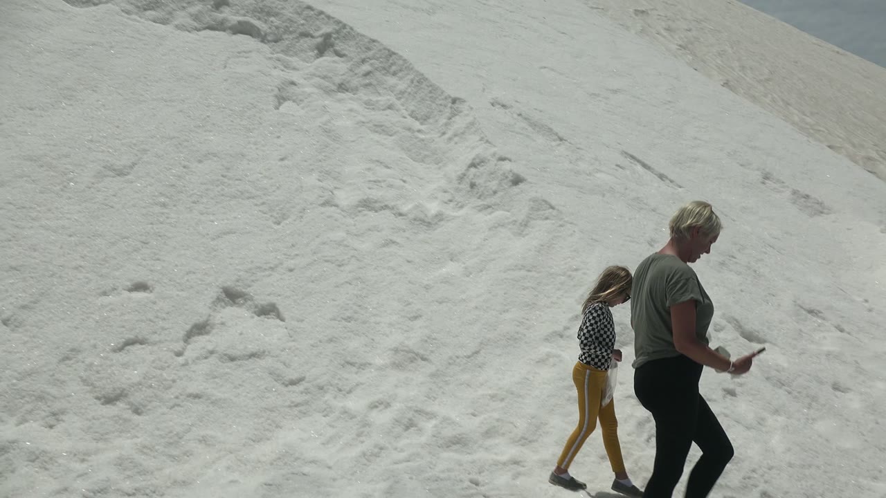 Adult walking as child moves on white sand