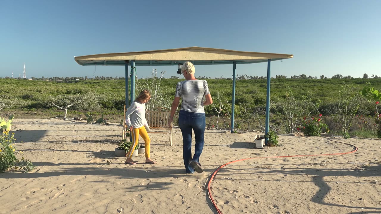 Child reaches the shelter while woman follows on sand.