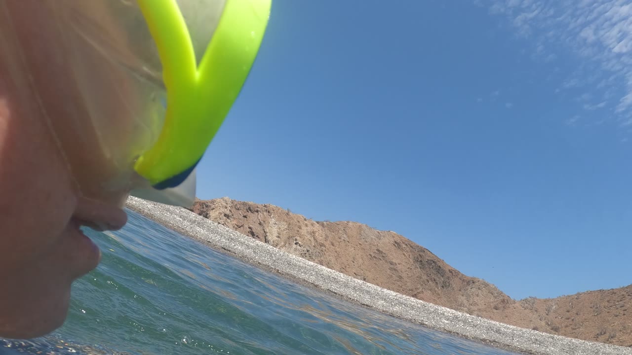 Snorkeler at the surface near rocky beach and hills.
