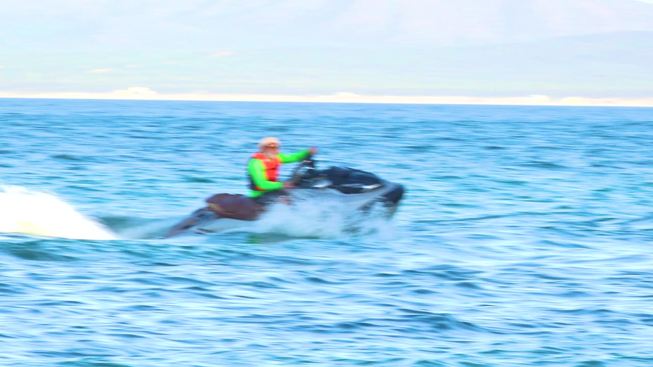 Watercraft rider speeding across the ocean with spray behind.