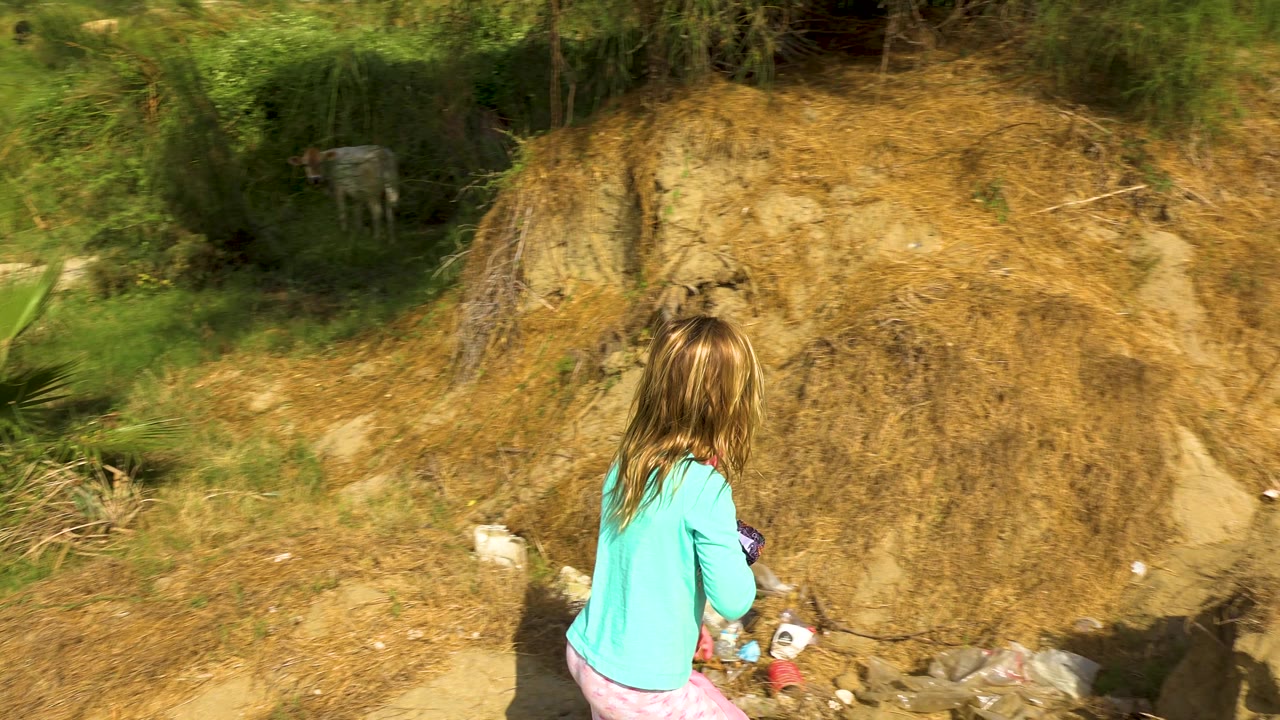 Girl walking away beside a dry eroded bank.
