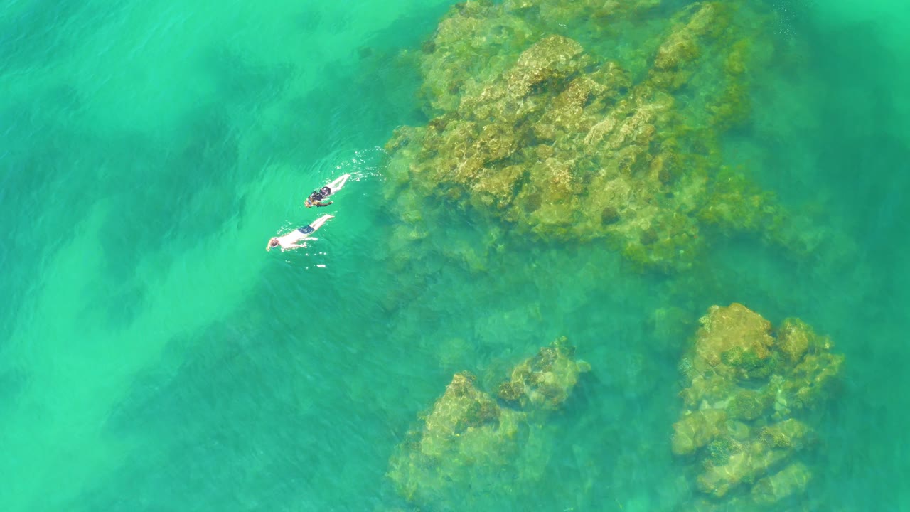 Snorkelers beside reef with underwater sand channels