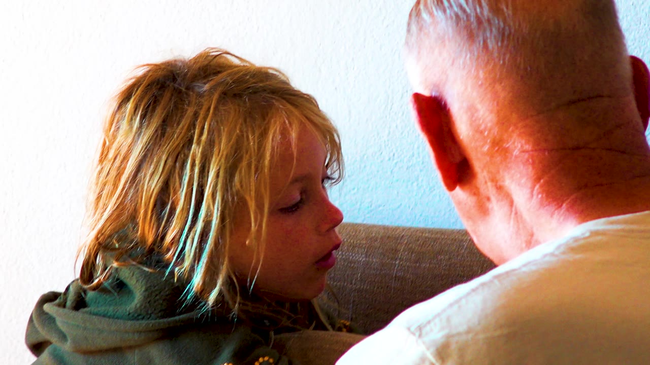 Young girl looks toward a man seated close beside her.