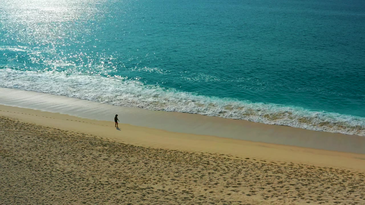 High drone composition over Desert Park Natural Reserve with the solitary figure near the waterline and stronger white foam spreading across the upper beach edge.