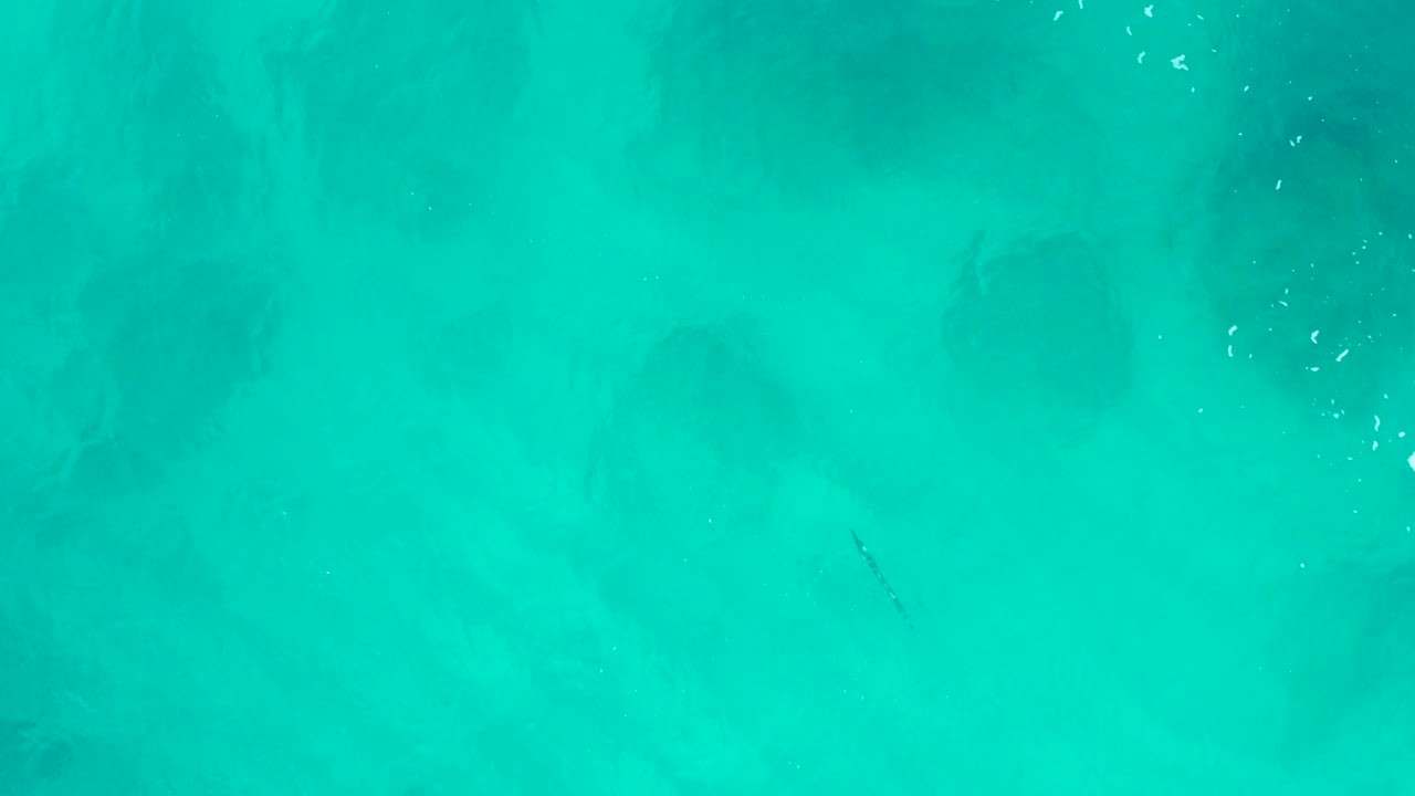 Top-down aerial water frame from Baja California Sur, Mexico, showing cloudy darker areas under the turquoise surface and no visible people.