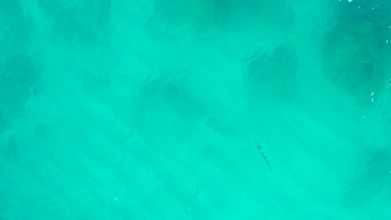 Turquoise water at Desert Park Natural Reserve fills the frame, with small pale bubbles near the upper area and darker underwater shapes visible below, no visible people.