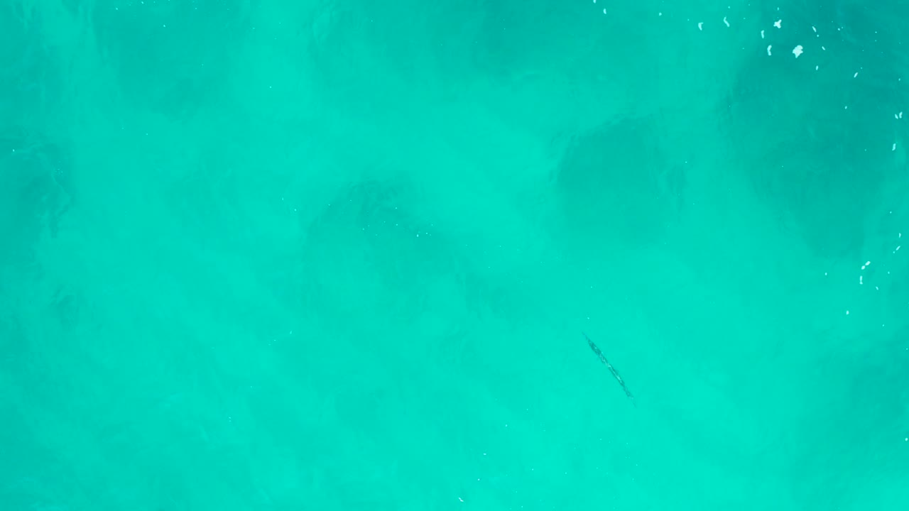 Top-down aerial view of turquoise water in Desert Park Natural Reserve, Baja California Sur, with faint dark submerged patches and no visible people.