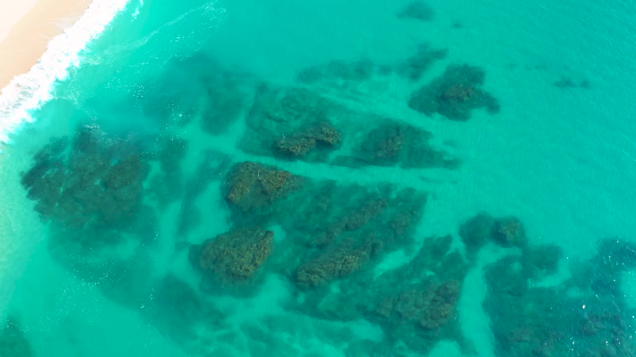 Overhead reef formations under turquoise water with white surf at left.