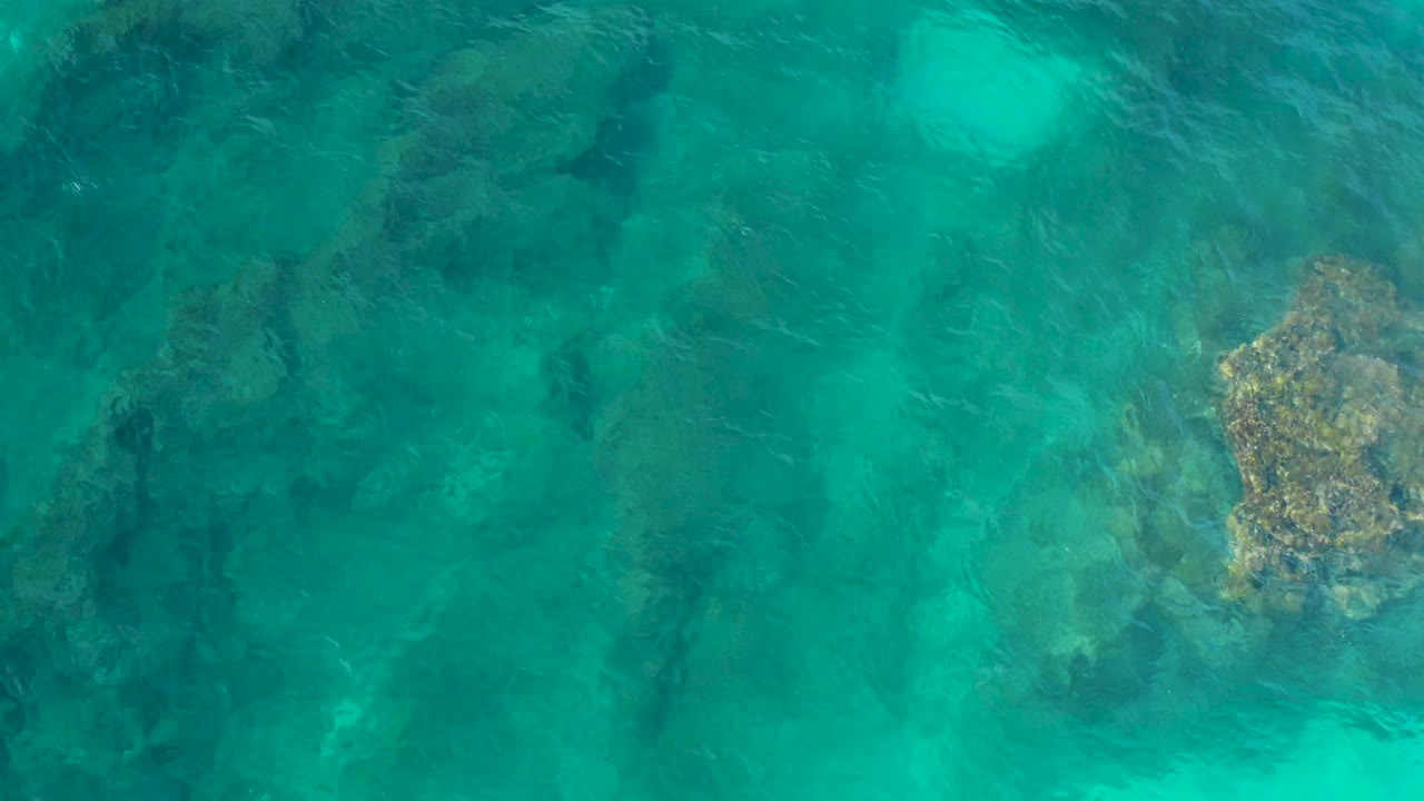 Submerged rock mass beneath green-blue ocean water