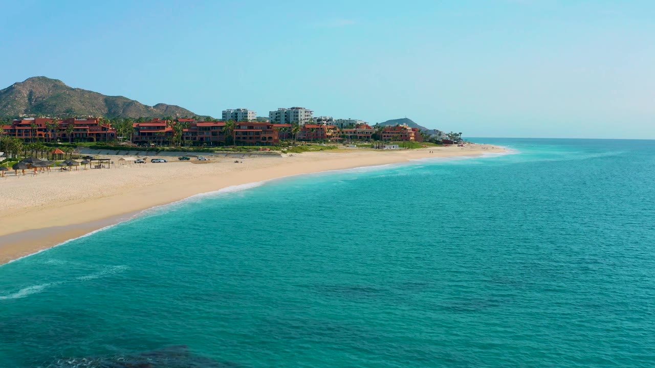 Third frame shows more open water on the right side of the Desert Park Natural Reserve beach, with the resort frontage and mountain foothills running along the left background and no visible people.