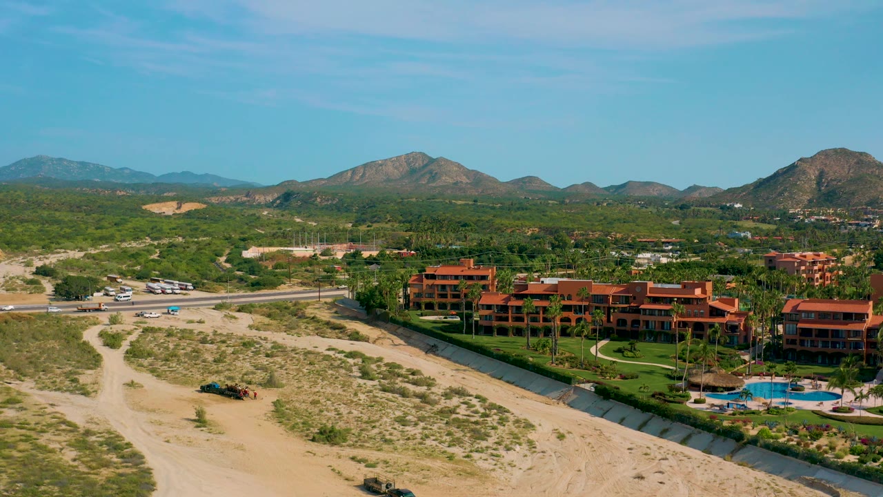 Desert resort with pool, dry wash, road, and mountains