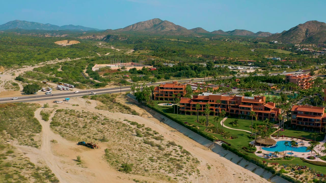 High aerial view of resort grounds, highway, desert brush, and mountain range.