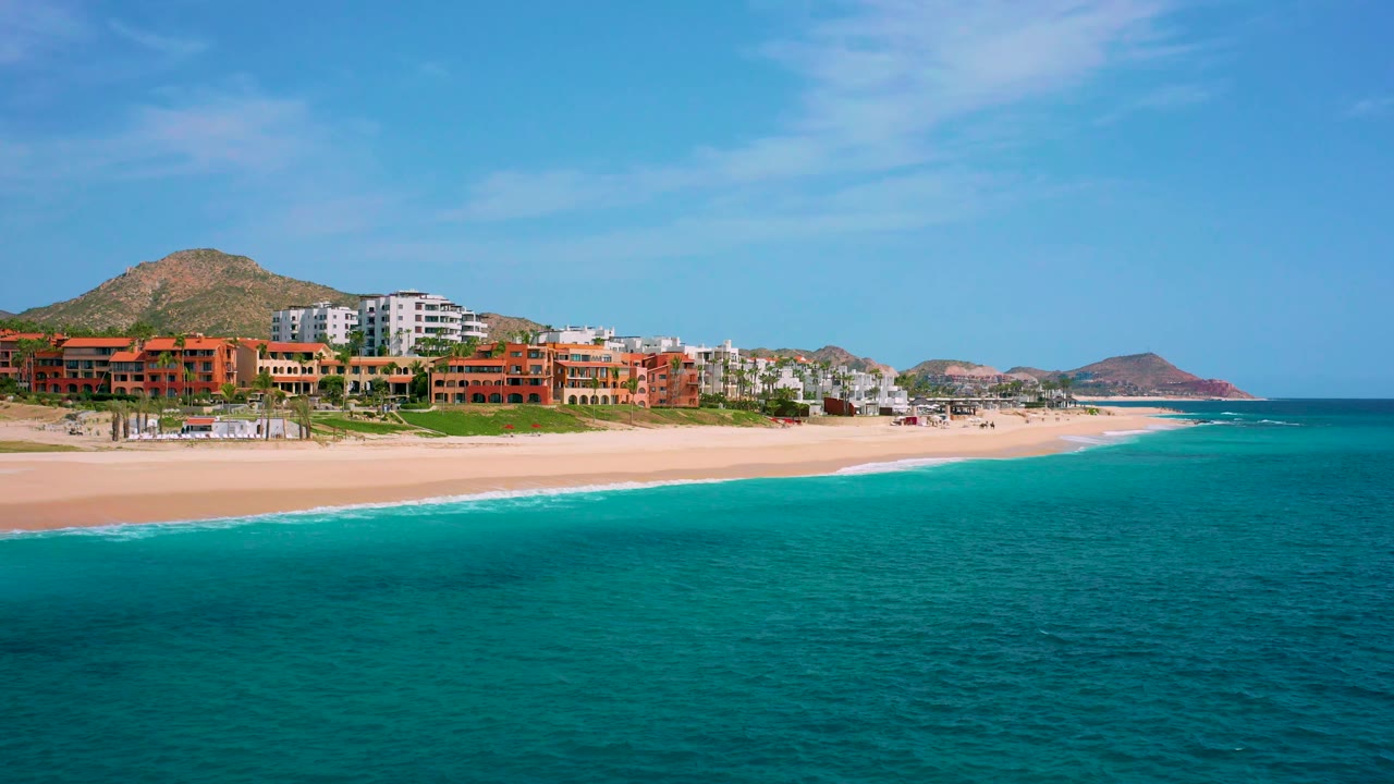 Ocean foreground with sandy resort beach and arid hillside
