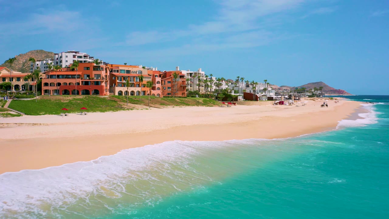 Resort buildings above beach with turquoise water along the right edge
