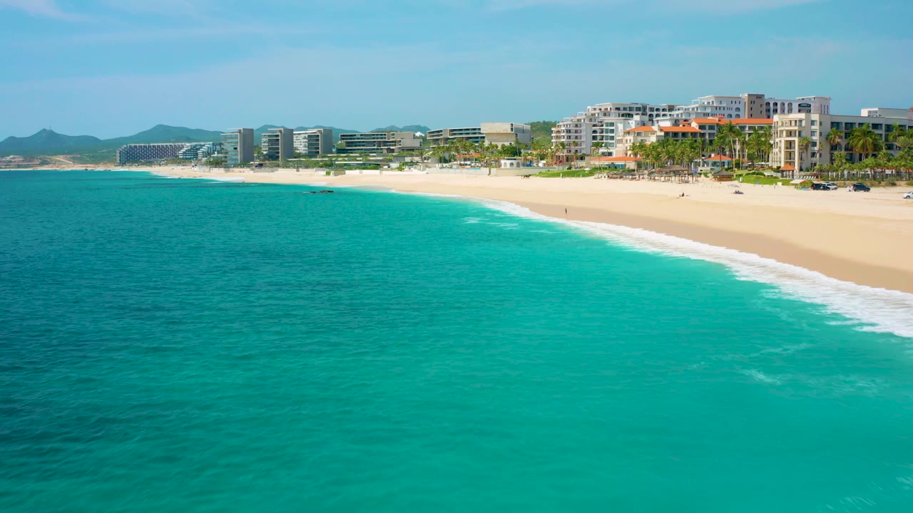 Aerial coastline with open water in front and beachfront buildings behind