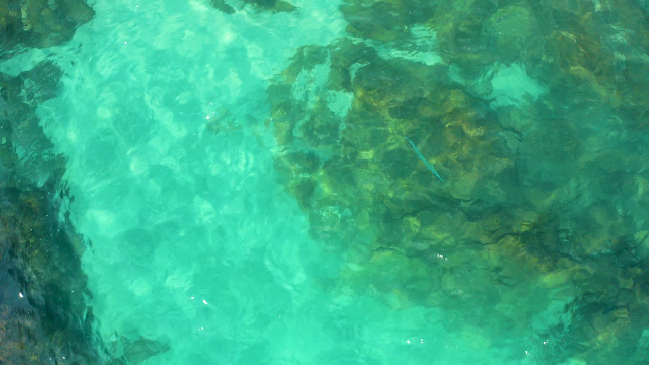 Turquoise water rippling over submerged rocks