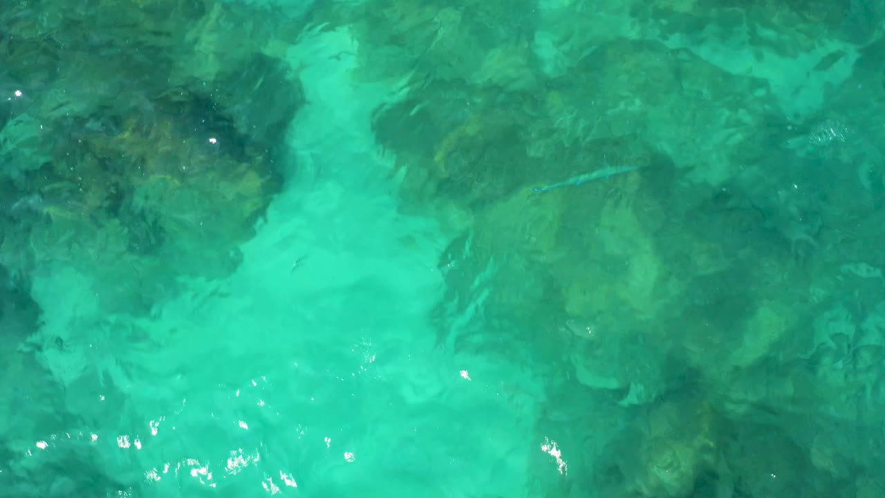 Clear green-blue water with darker seabed patches.