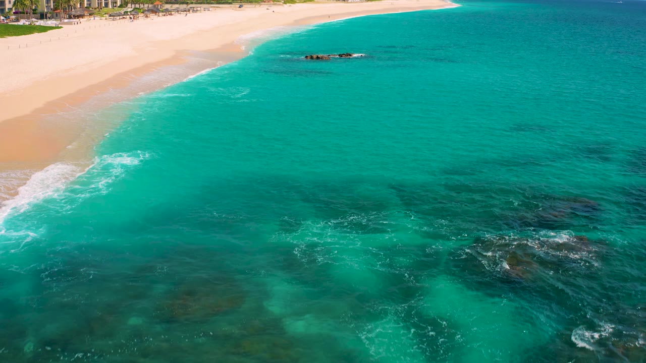 Clear turquoise ocean beside a curving sandy shoreline