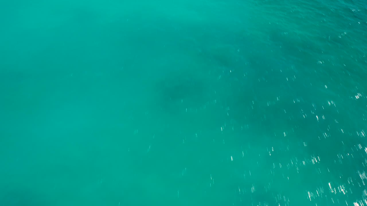 Overhead turquoise ocean water in Baja California Sur, Mexico, with soft ripples, muted darker patches beneath the surface, and no visible people.
