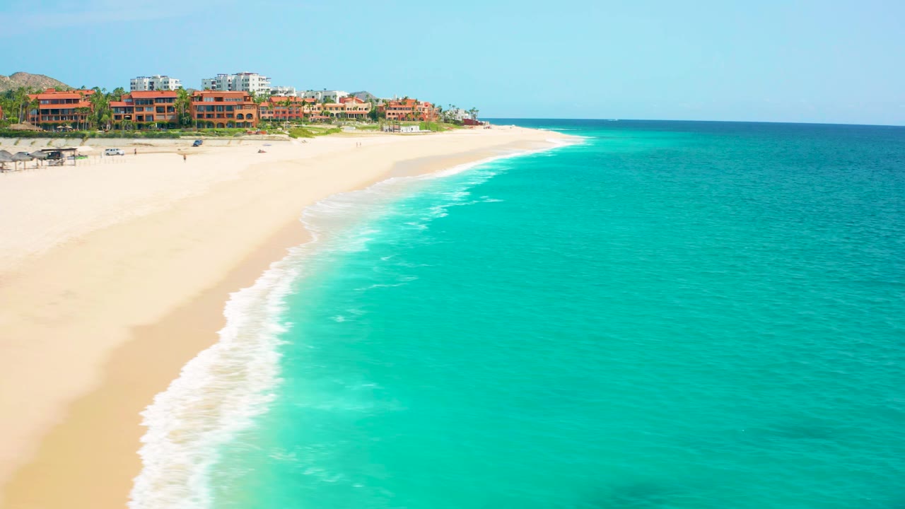 Aerial shoreline with white surf washing onto sand