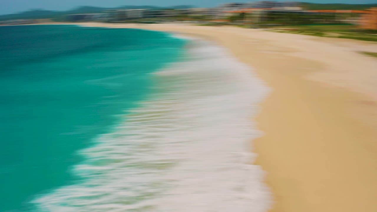 Aerial view over Desert Park Natural Reserve in Baja California Sur with the foamy surf line and beach still motion-blurred, and no visible people.