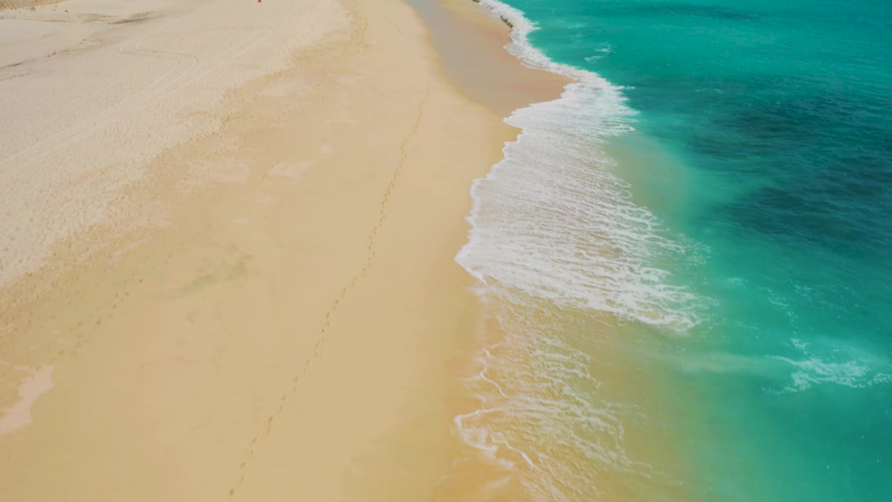 Aerial frame showing a diagonal band of surf between pale beach and darker blue water at Desert Park Natural Reserve in Baja California Sur.