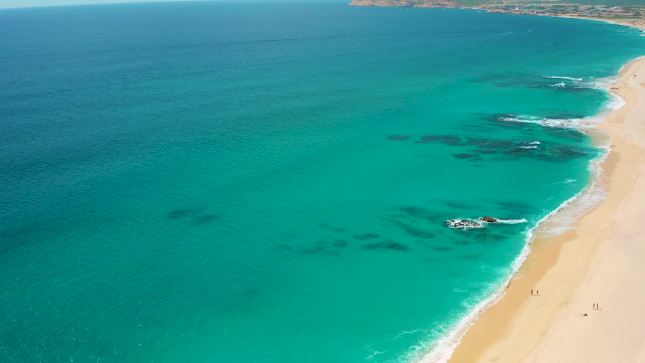 Aerial coastline with ocean, surf, and pale sand