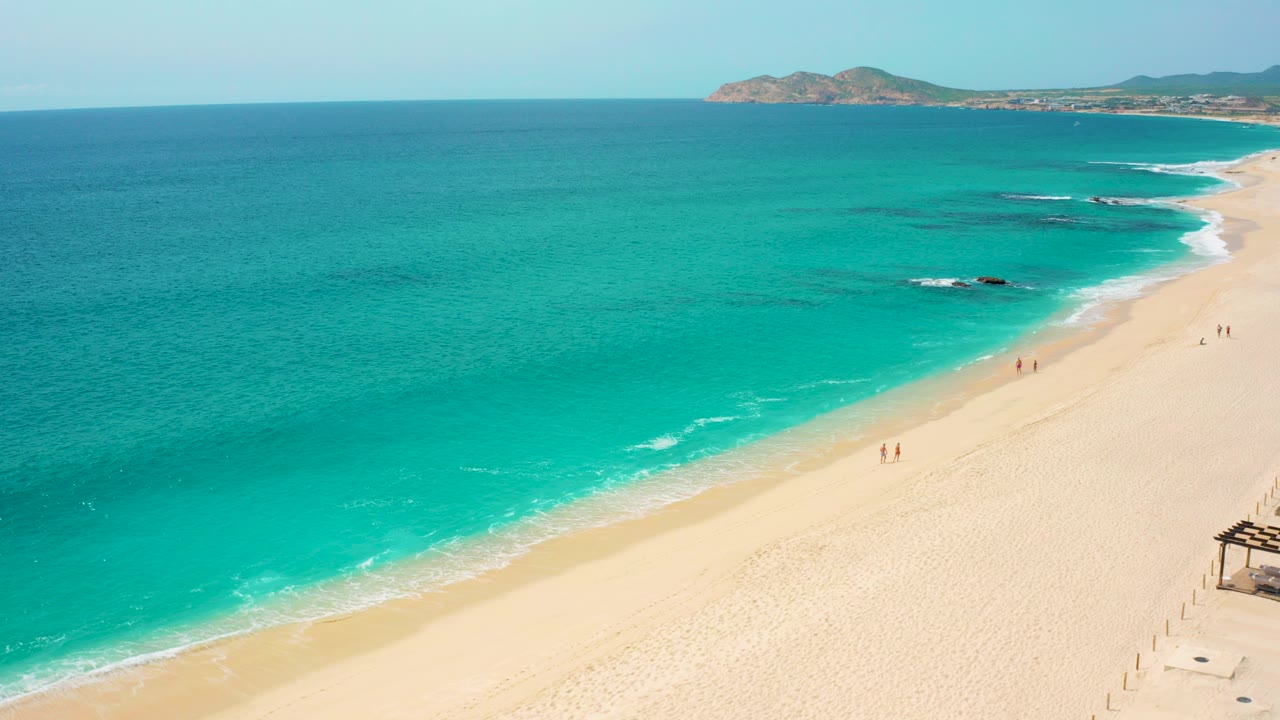 High aerial view of turquoise ocean beside a pale sandy beach.