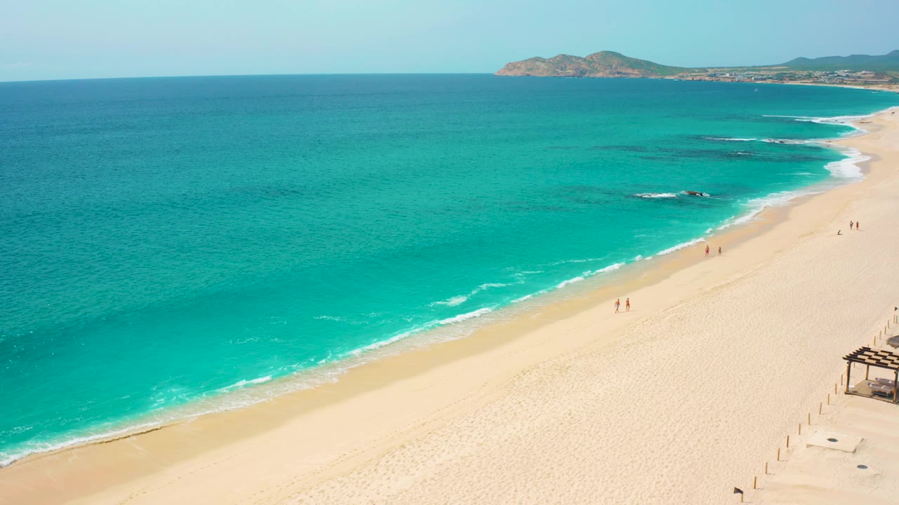 Desert Park Natural Reserve aerial frame with open turquoise sea filling most of the image, pale sand at right, small surf breaks, and a rocky headland beyond the beach.