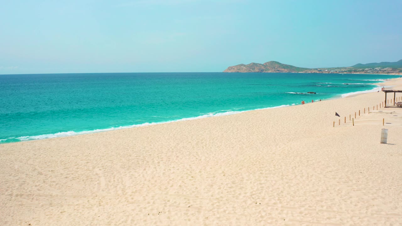 Beach shoreline with turquoise sea and distant rocky land