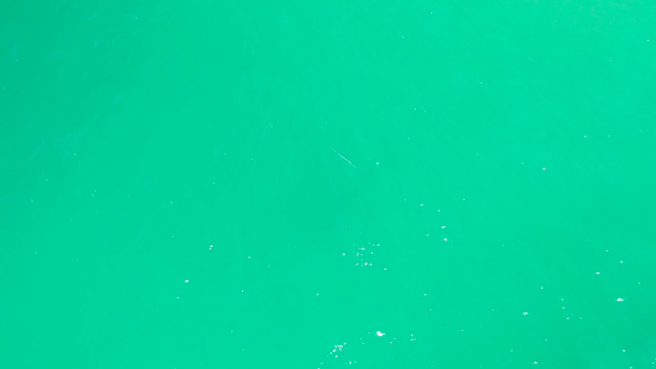 Turquoise ocean plane at Dreams Los Cabos BCS Mexico with scattered foam specks and a simple uninterrupted surface view, with no visible people.