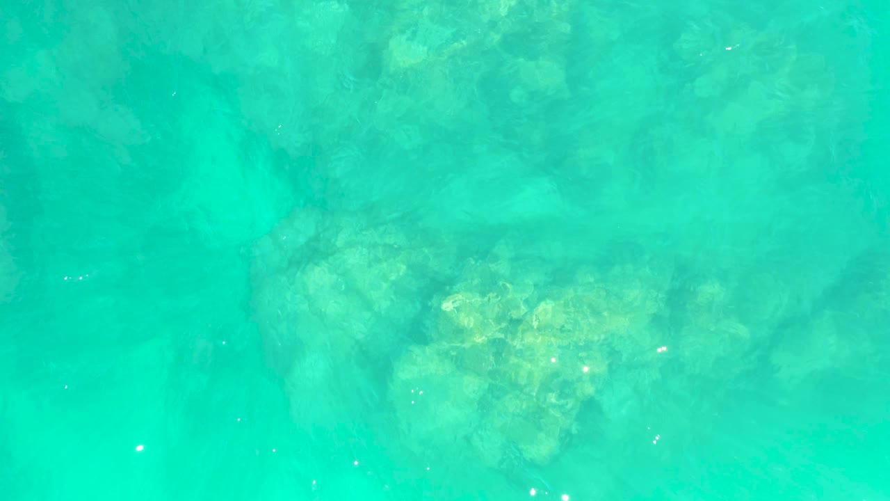 The frame shows calm turquoise ocean at Marquis Los Cabos BCS Mexico with faint rock forms under the surface and no visible people or shoreline.