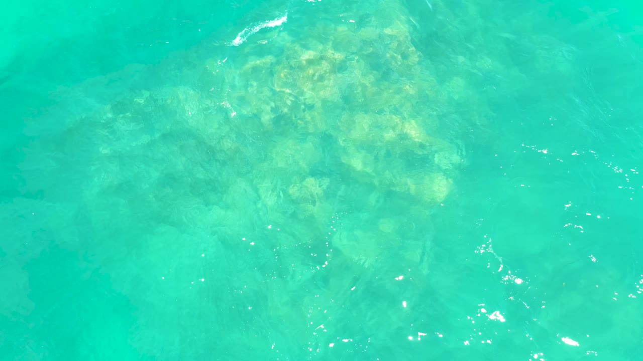 Overhead view of clear aqua water with clustered rocks visible below the surface at Marquis Los Cabos BCS Mexico, with no visible people.