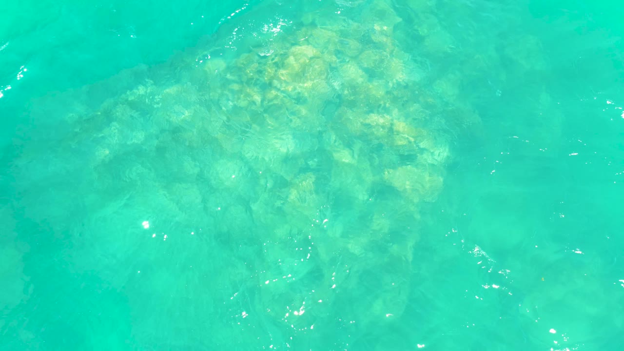 Bright turquoise ocean surface over a concentrated underwater rock patch at Marquis Los Cabos BCS Mexico, with no visible people.