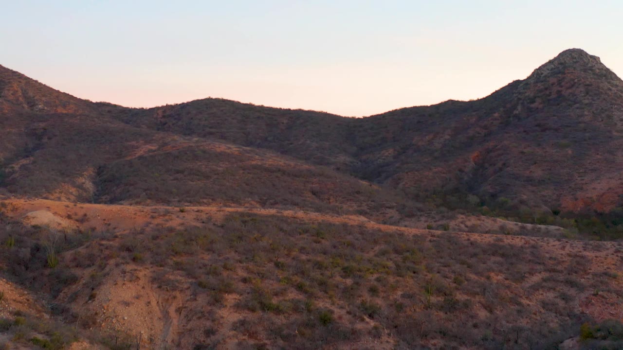 Wide mountain valley with sandy eroded foreground and scrub.