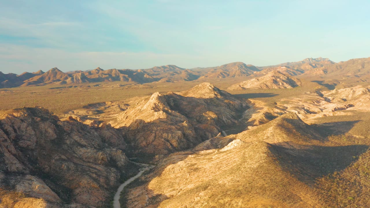 Rocky desert basin with long shadows and winding road