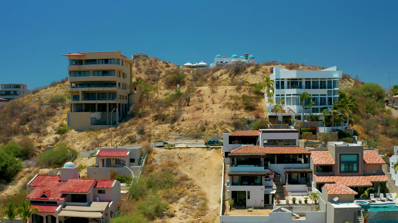 Residential hillside with foreground roofs and dry vegetation