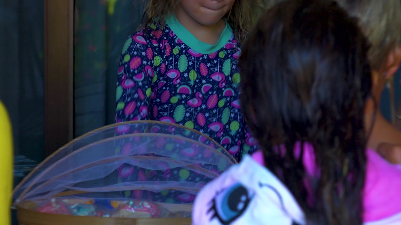 A closer crop shows children's swim clothing and wet hair around the translucent dome on the party table in San Jose del Cabo, Mexico.