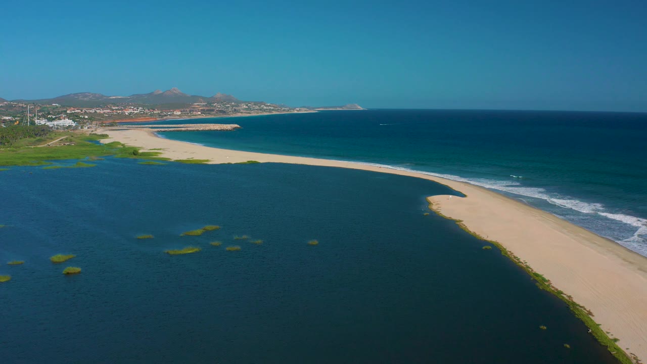 San Jose del Cabo BCS Mexico aerial frame with scattered green patches in the lagoon, a curving sand point, darker ocean water, and no visible people.