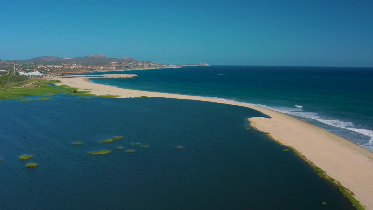 Aerial beach and lagoon with small wave lines along the ocean shore.