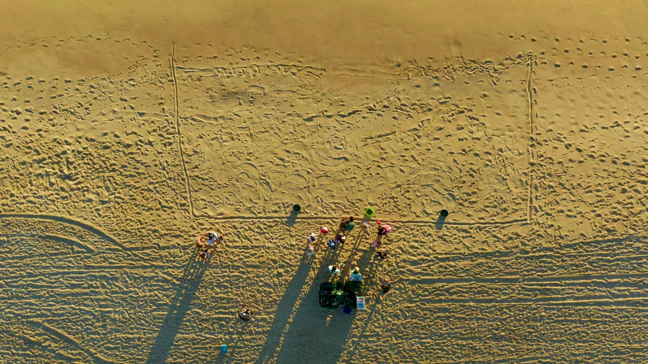 Small group on sandy beach seen from directly above.