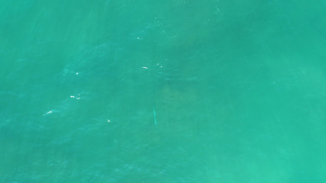 Aerial view over turquoise water at San Luis Beach East Cape Los Cabos, Mexico, with darker underwater bands visible beneath the rippled surface and no visible people.