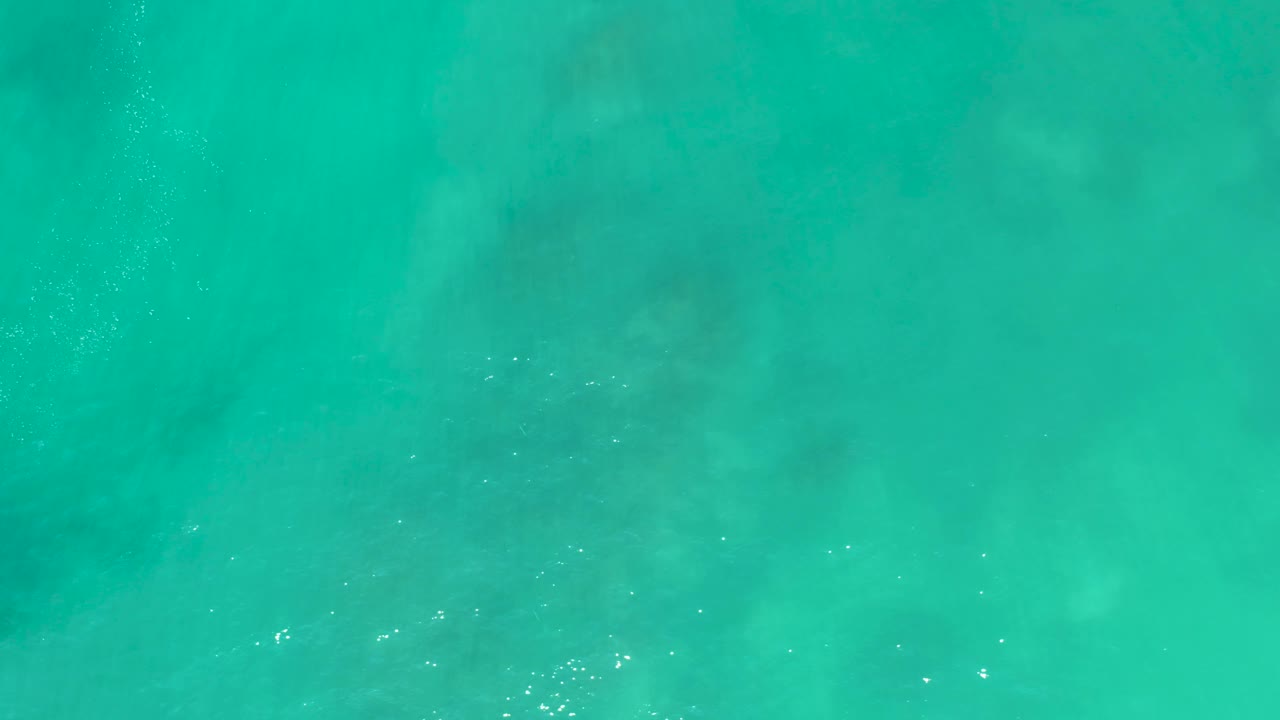 Turquoise ocean water at San Luis Beach East Cape Los Cabos Mexico shows darker underwater shapes beneath a lightly rippled surface, with no visible people.