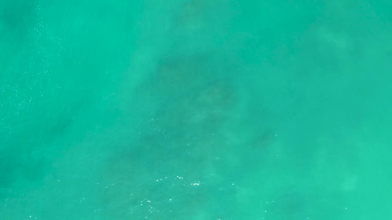 An overhead frame of San Luis Beach East Cape Los Cabos Mexico water shows pale seabed patches under clear turquoise surface ripples, with no visible people.