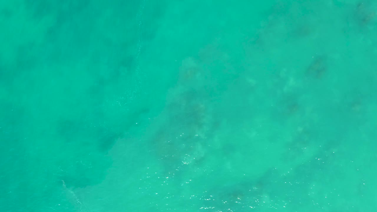 Transparent turquoise water at San Luis Beach East Cape Los Cabos, where mottled darker shapes sit beneath the rippled surface with no visible people.
