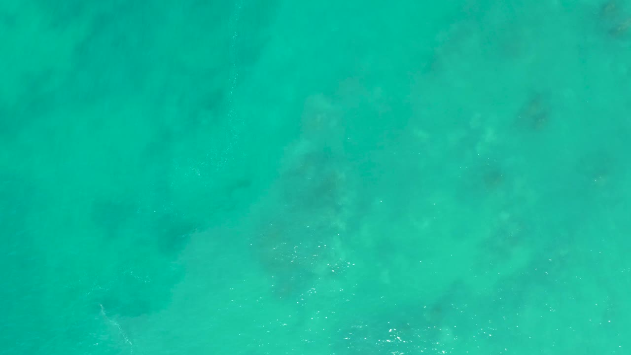 Overhead view of turquoise ocean at San Luis Beach East Cape Los Cabos, with subdued seabed patches showing through and no visible people.