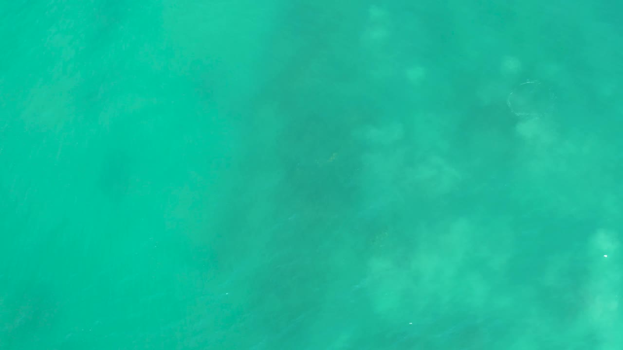 Turquoise ocean water covers the frame as soft pale underwater shapes drift in visibility over the seabed at San Luis Beach, East Cape Los Cabos, Mexico, with no visible people.
