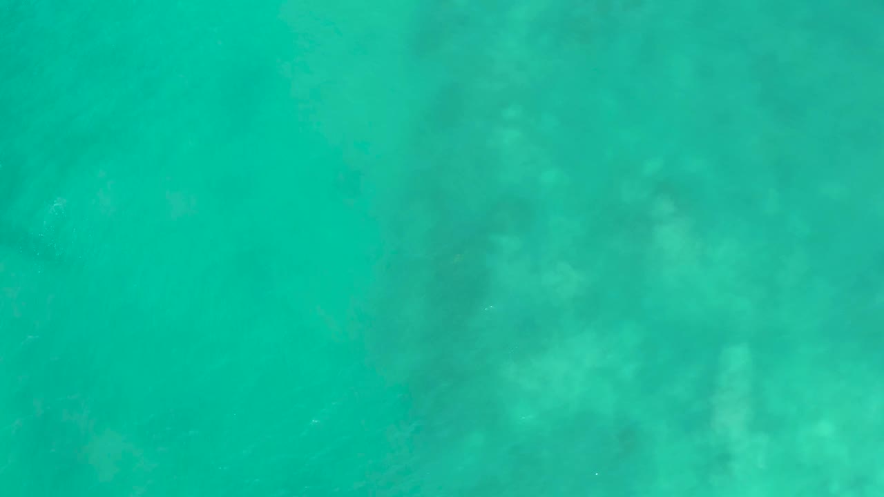 Clear green-blue water fills the frame at San Luis Beach East Cape Los Cabos, Mexico, with faint mottled seabed shapes and no visible people.
